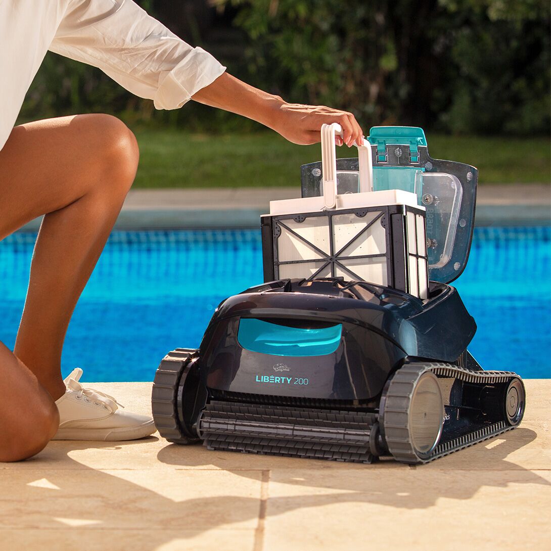 Lifting the top-load filter basket out of the Dolphin Liberty 200 poolside